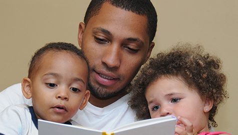 parent reading a book to two children