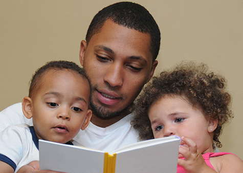parent reading a book to two children